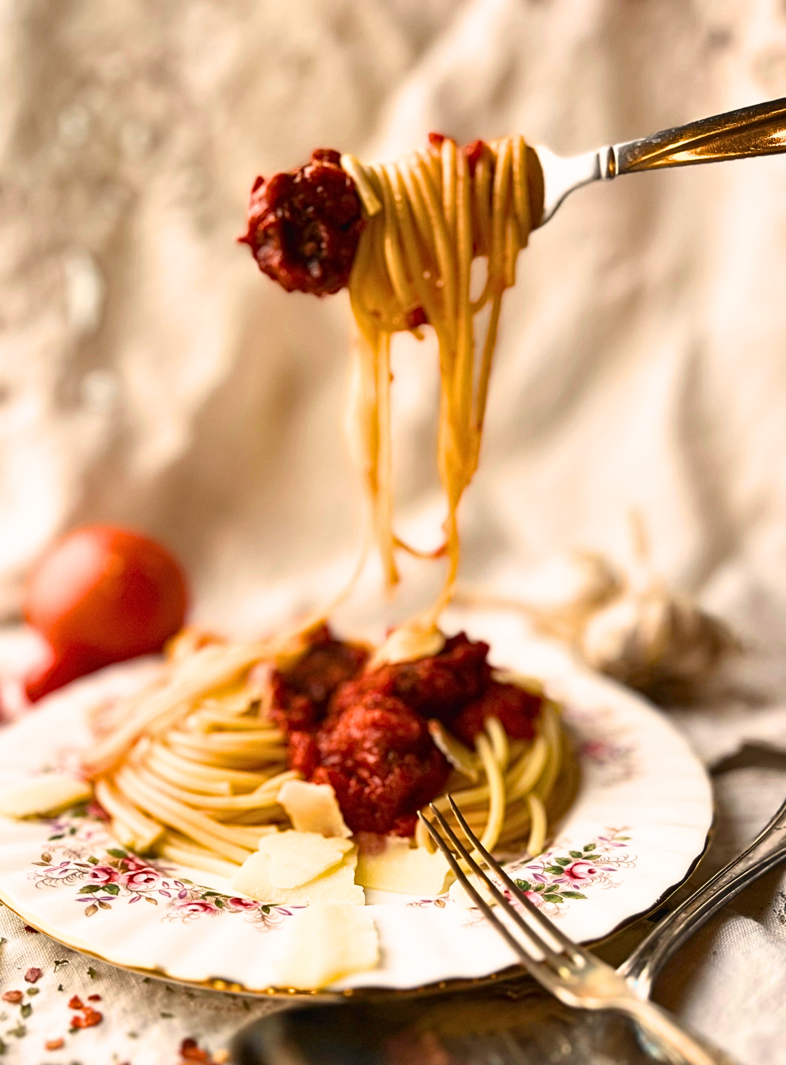Georgia's spiggetta (spaghetti and meatballs) on a pink floral plate with a fork holding up some of the spaghetti and a meatball on the end.