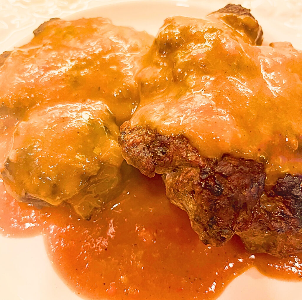 Two pieces of Salisbury Steak on a white plate.