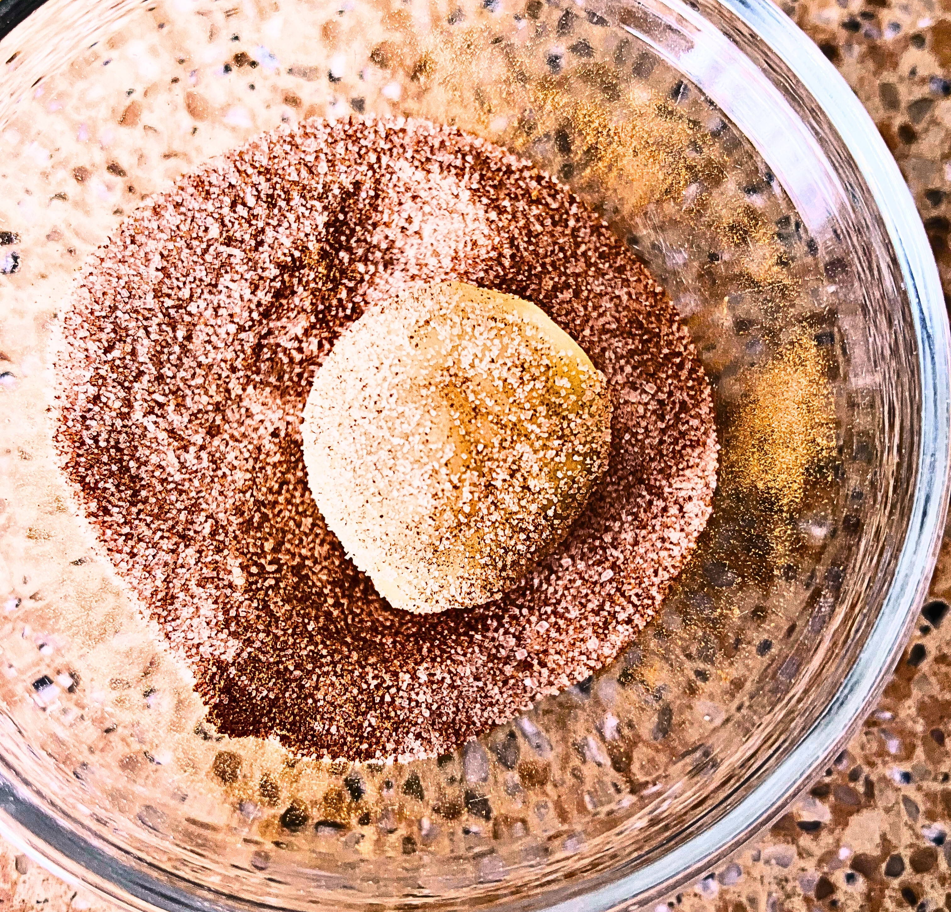 Rolling cookie dough in a cinnamon sugar mixture in a glass bowl.