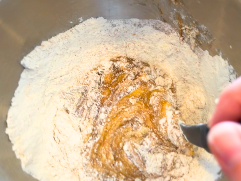 A woman mixing a brown liquid with flour.