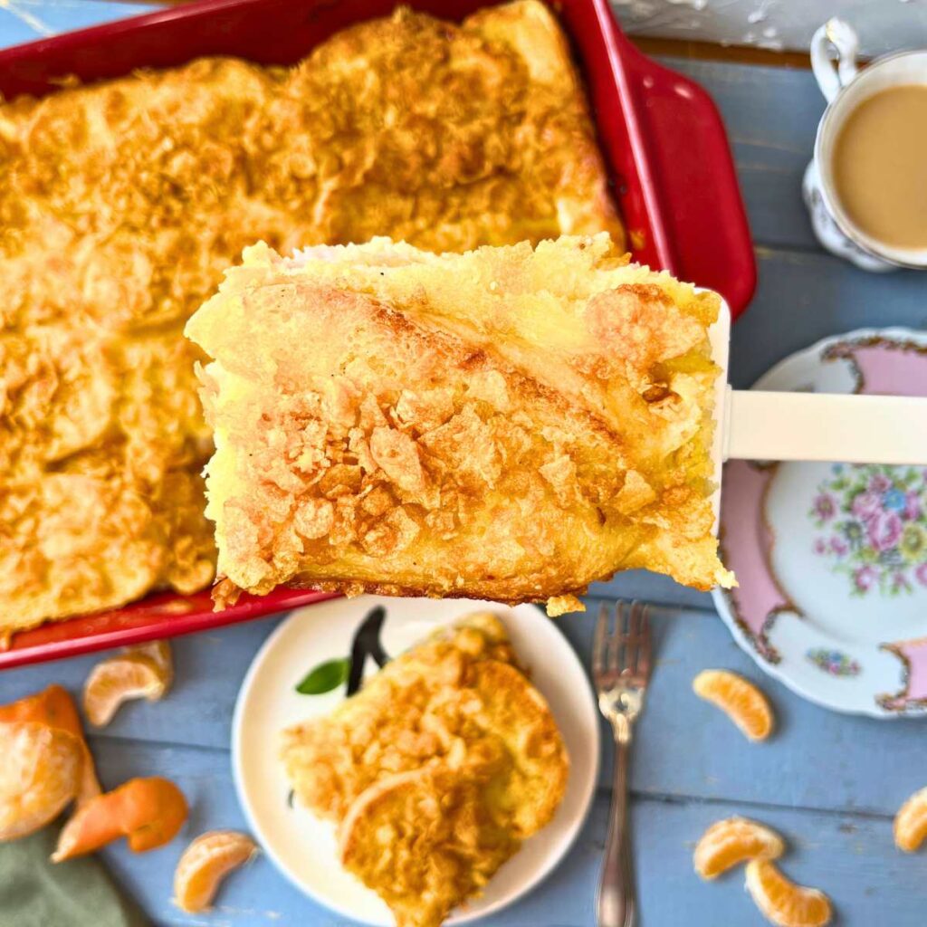 A woman is holding a large white spatula full of breakfast casserole. There is more in the background.