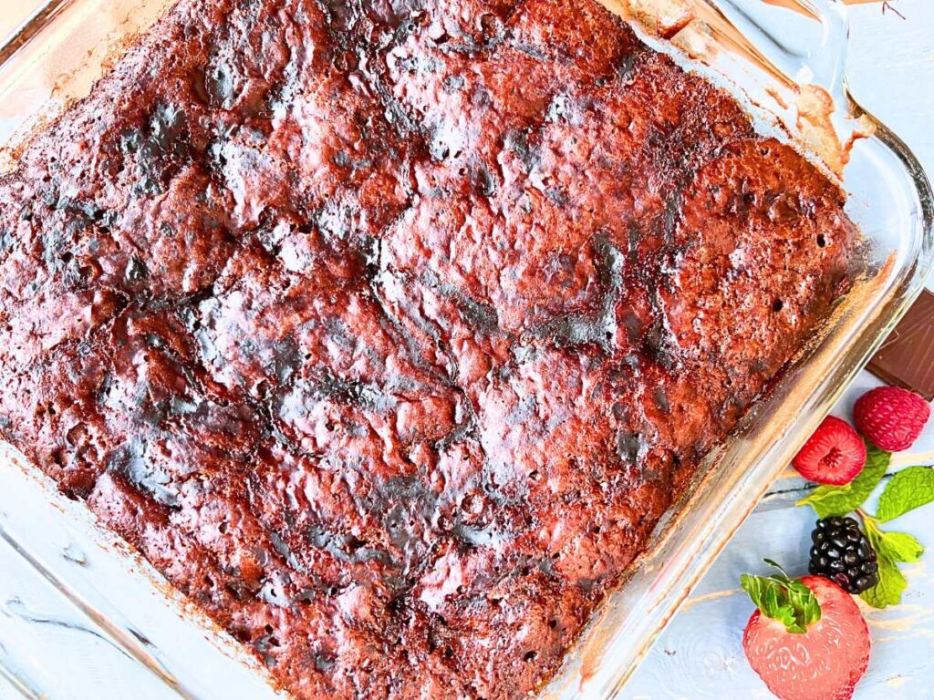 A baked chocolate pudding cake in a glass square casserole dish.