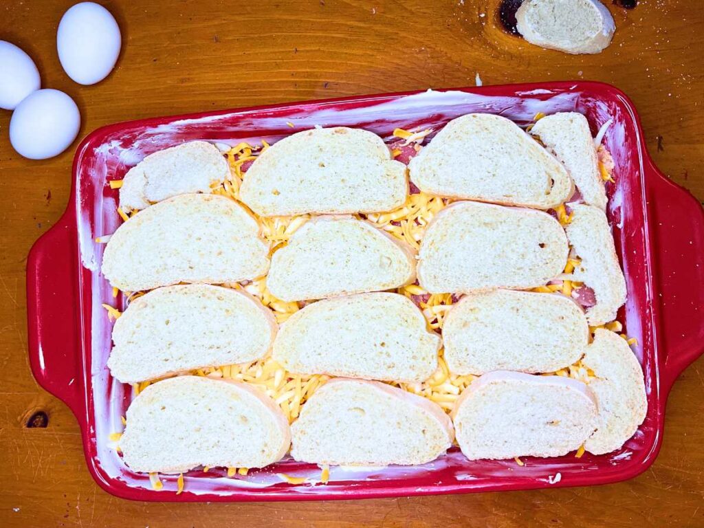 A red casserole dish with meat, cheese and bread inside.