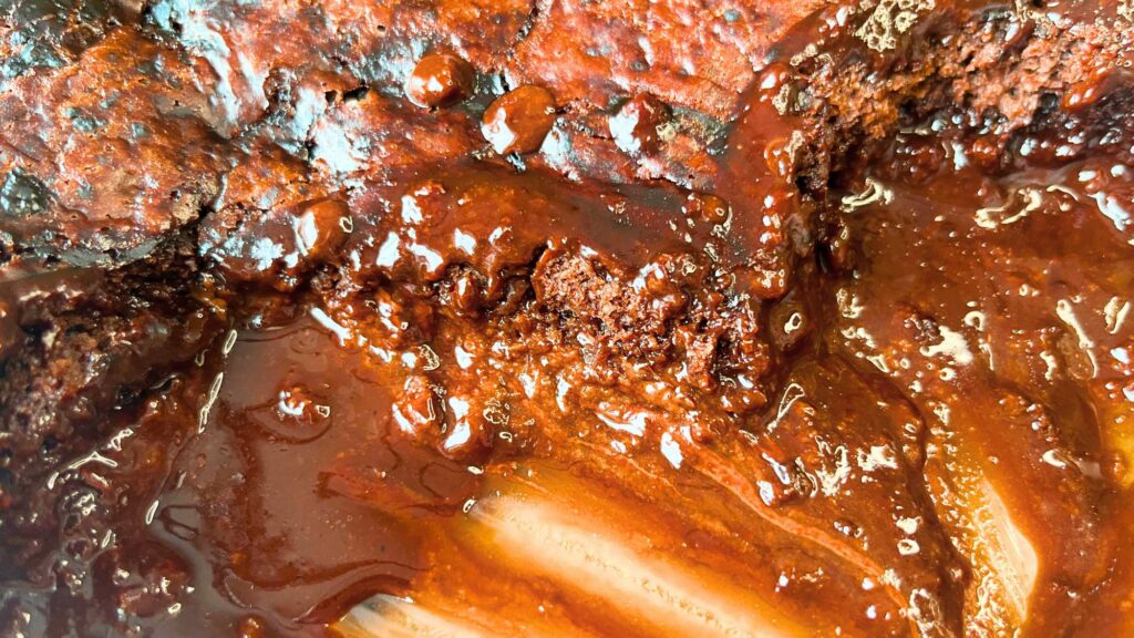 A chocolate cake with a fudge sauce in the bottom is in a glass casserole dish.