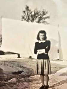 An antique picture of a woman standing in front of laundry drying.