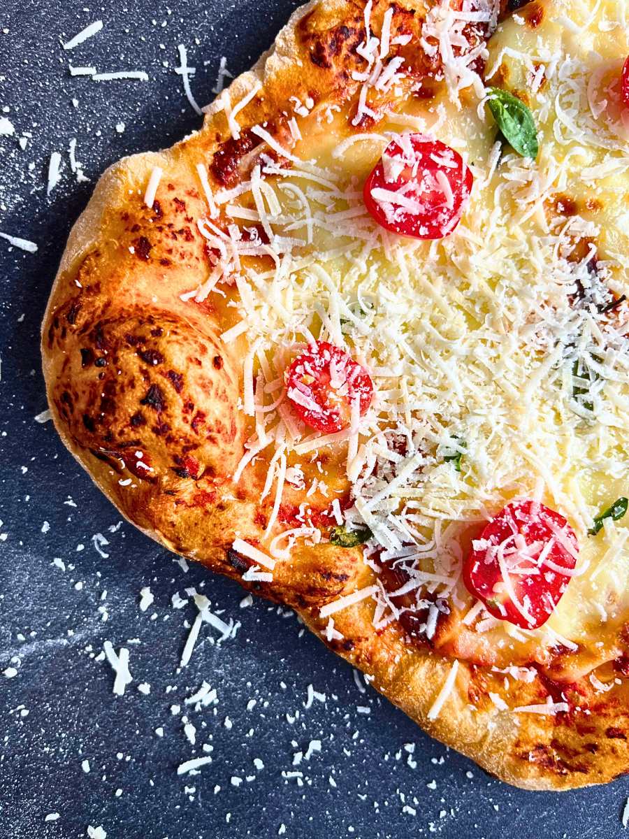 A baked margarita pizza with grated parmesan cheese on top.