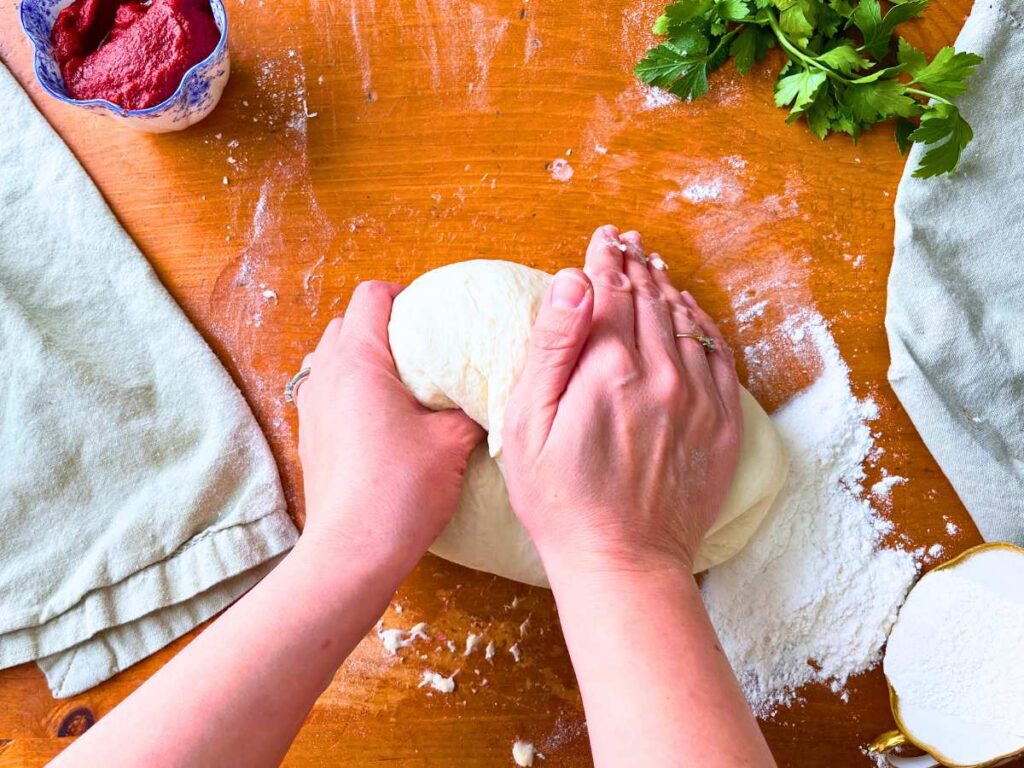 A woman is kneading pizza dough.