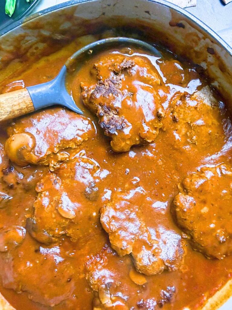 A Dutch oven with salisbury steaks in mushroom gravy.
