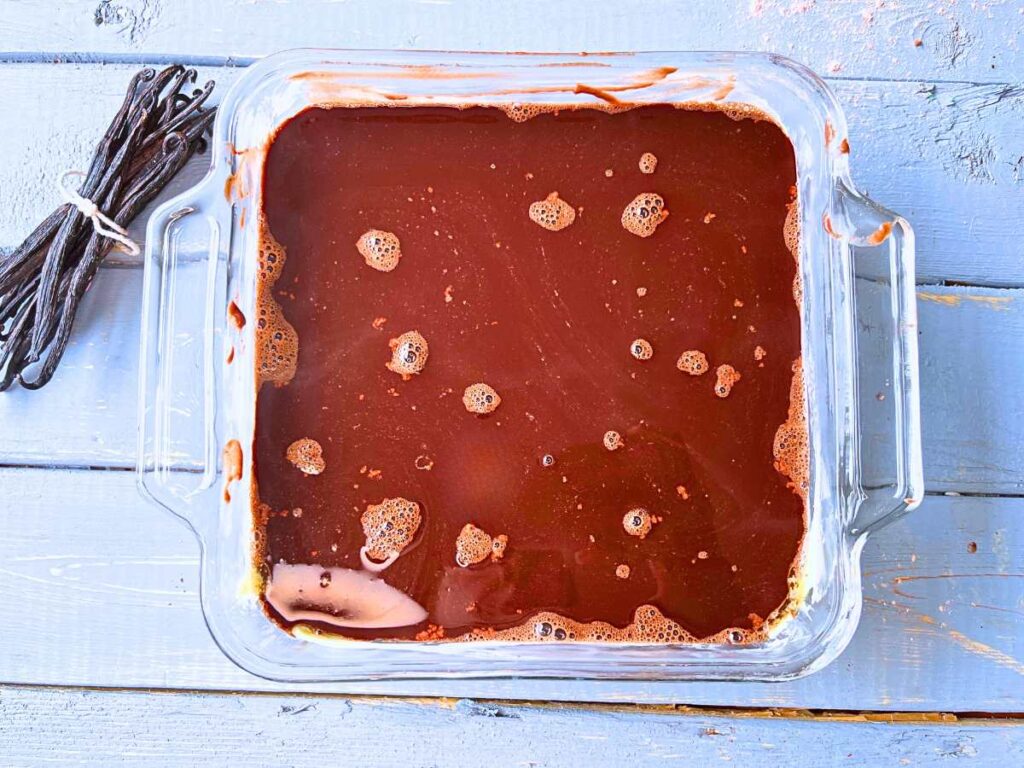 A glass casserole dish with an unbaked chocolate pudding cake inside.