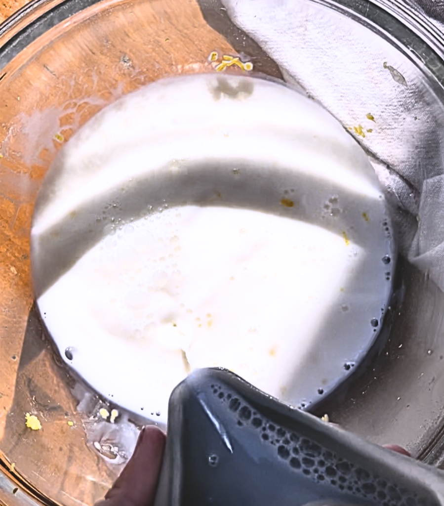Milk being poured into a bowl with lemon zest