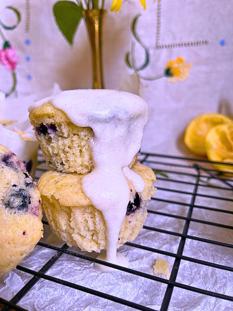 Stacked Lemon blueberry muffins with vanilla glaze funning down the side. 