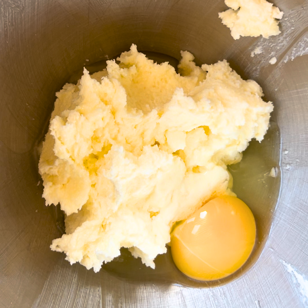 Creamed butter and sugar with a cracked egg in a bowl