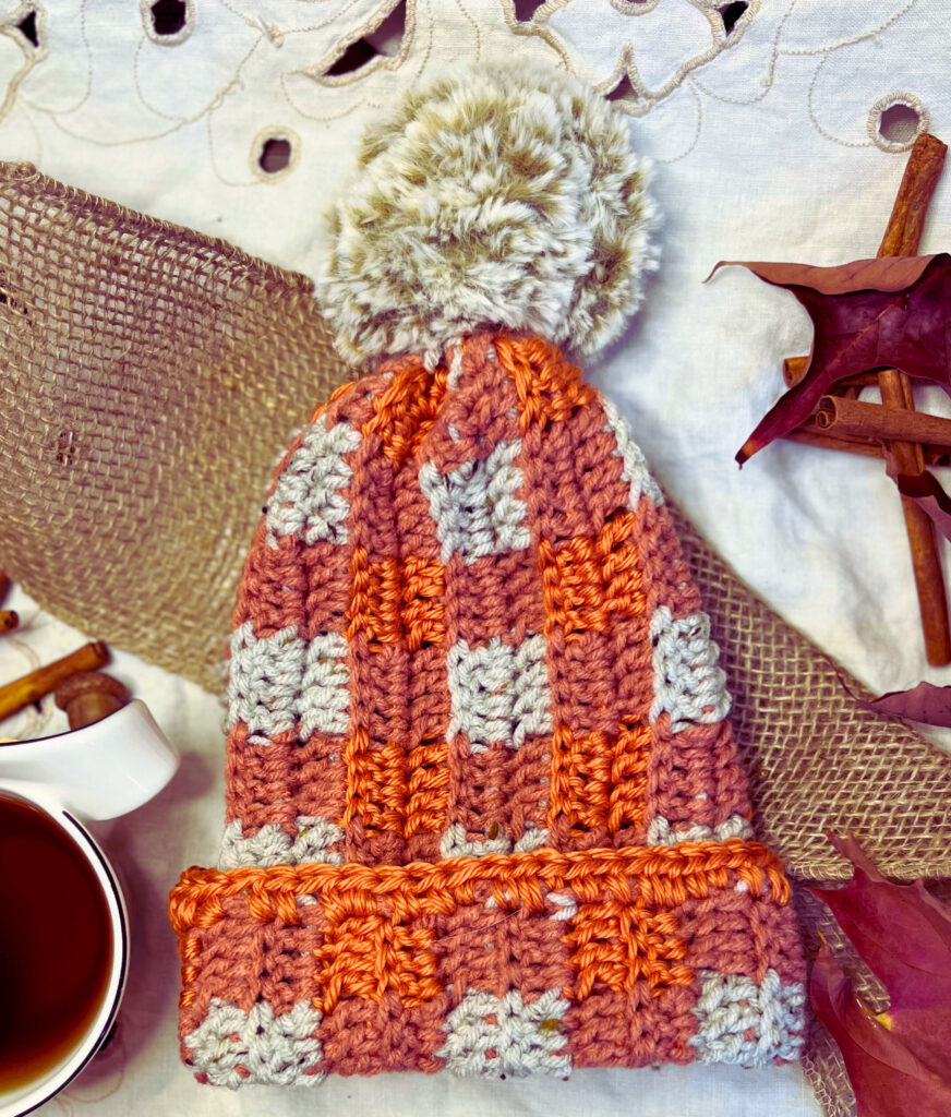 orange and grey double crochet toque with a brown fur pompom