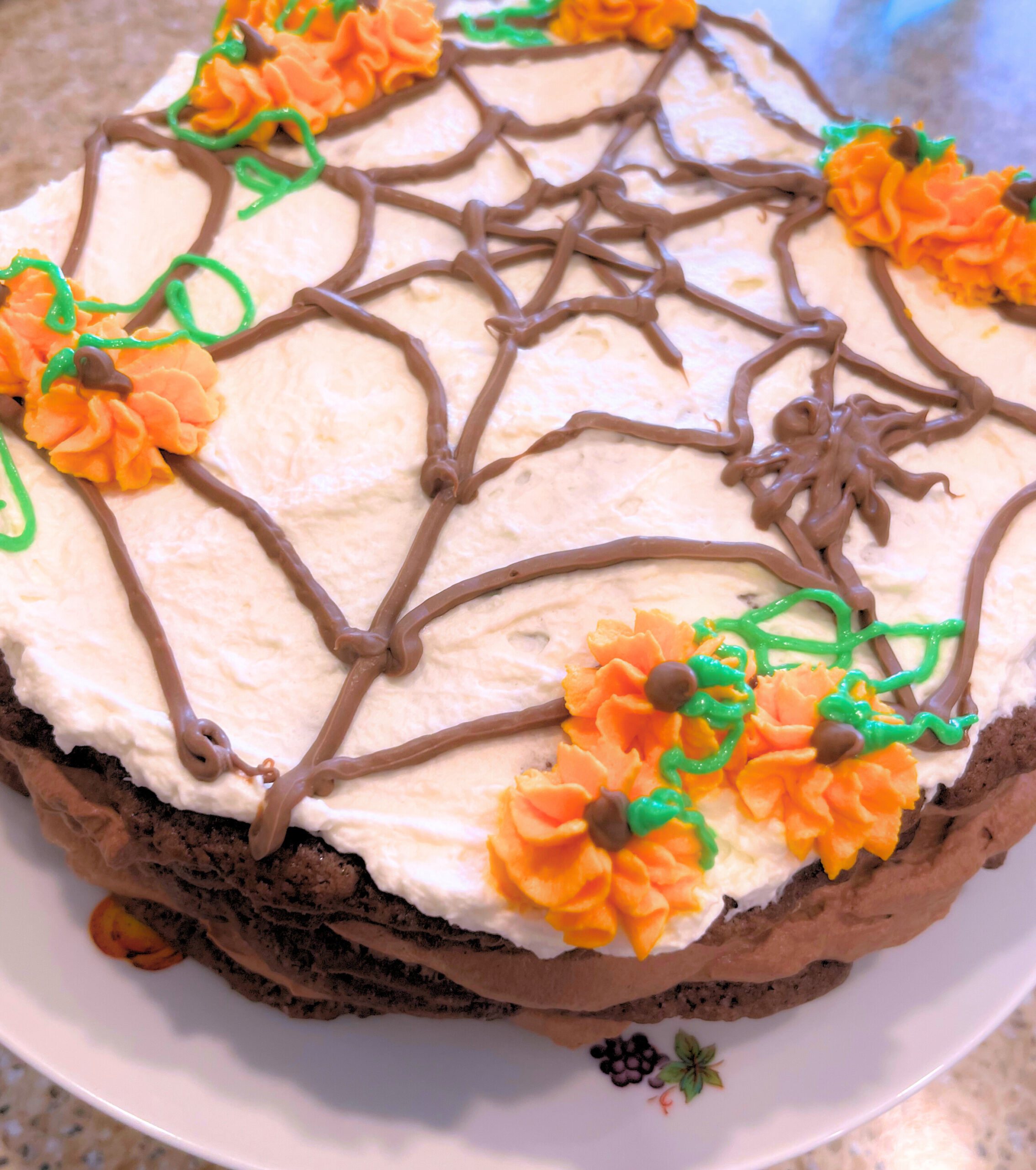 Chocolate Caramel Torte decorated with chocolate spider web and orange pumpkins with green icing vines