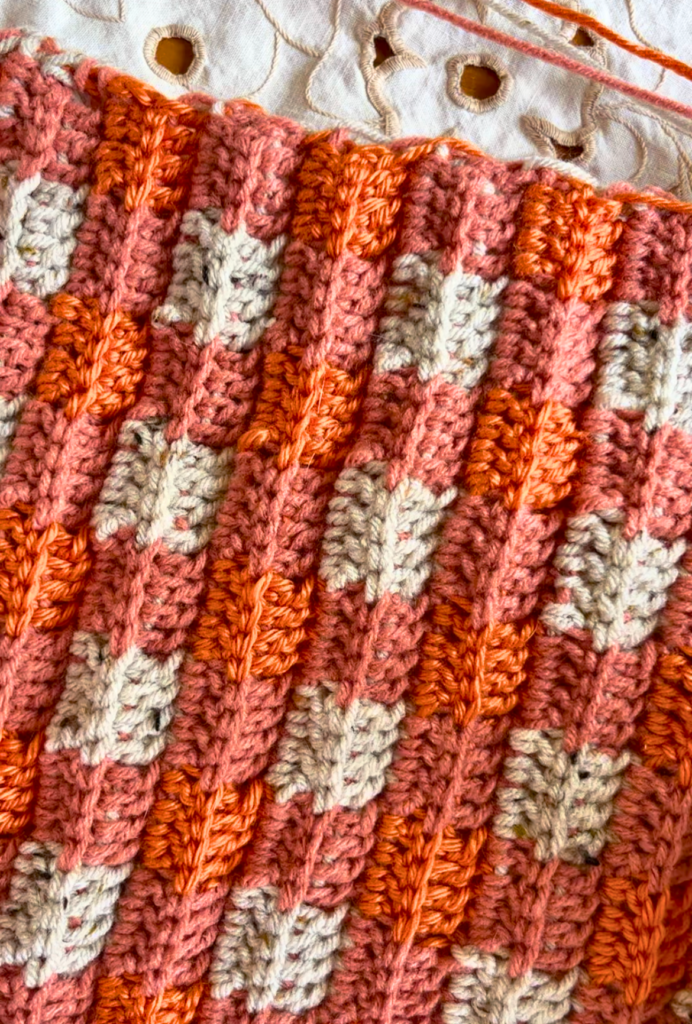 Double crochet hat with orange and grey in a buffalo plaid pattern