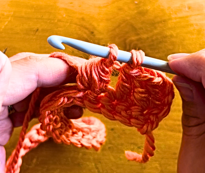 orange yarn on a crochet hook. Puff stitch