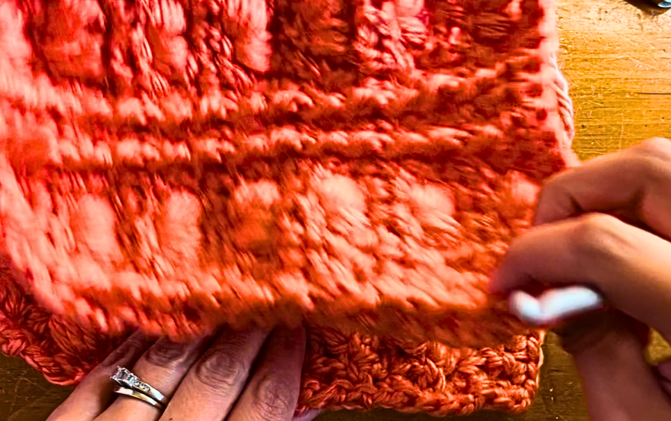 folding a an orange piece of crochet material in half