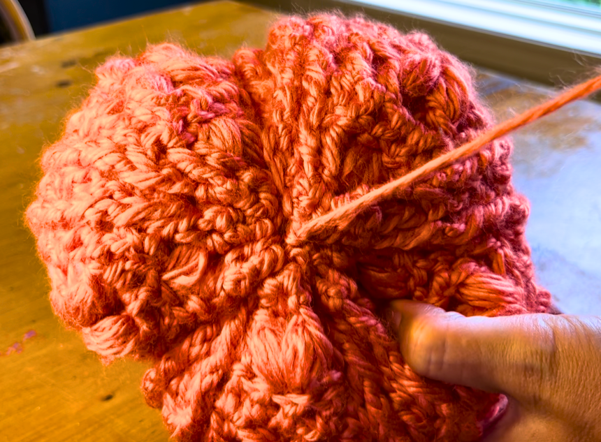 orange crochet pumpkin with a long piece of yarn