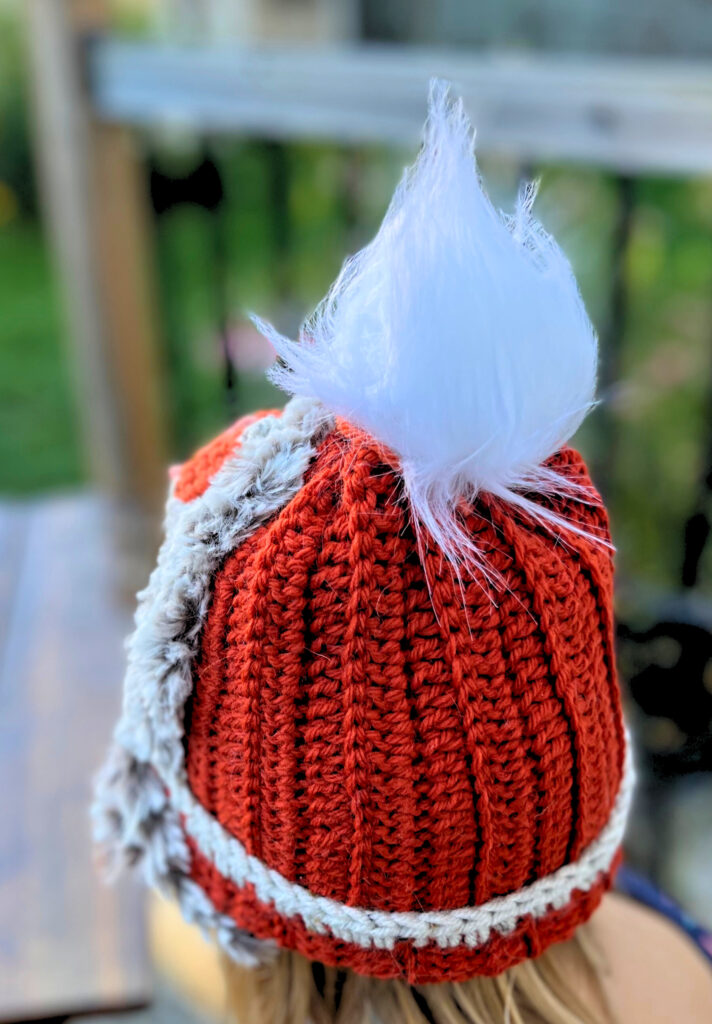 Orange crochet hat with a white faux fur pompom