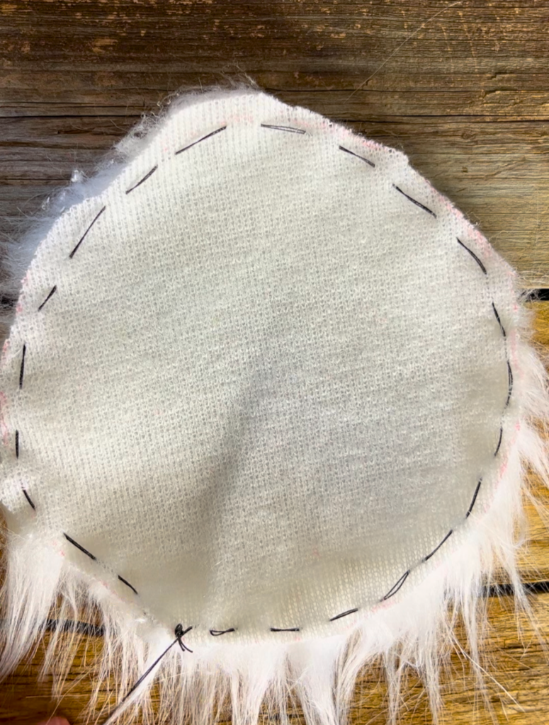 faux fur material with a running stitch in black thread around the circumference