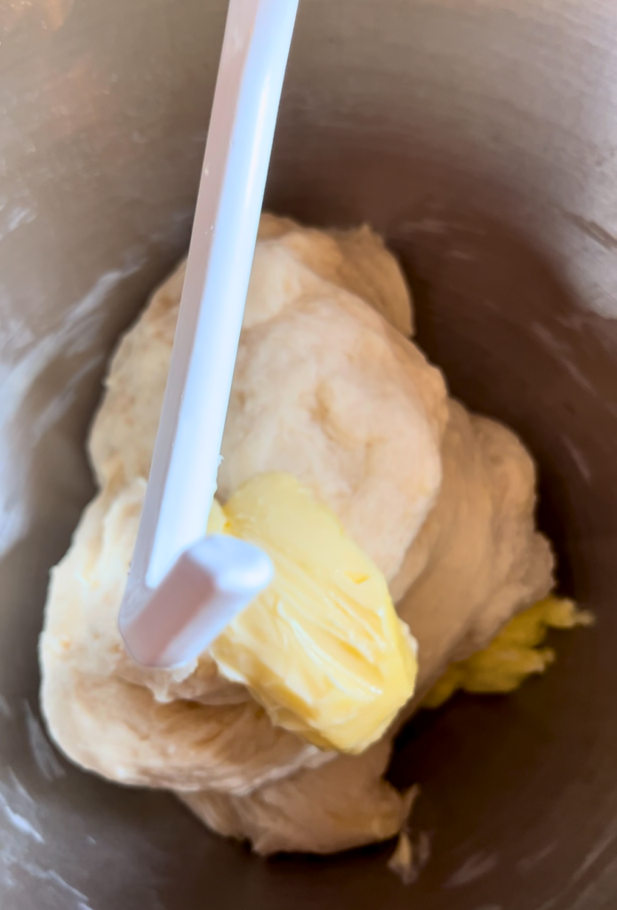 dough and butter in a silver bowl with a dough hook