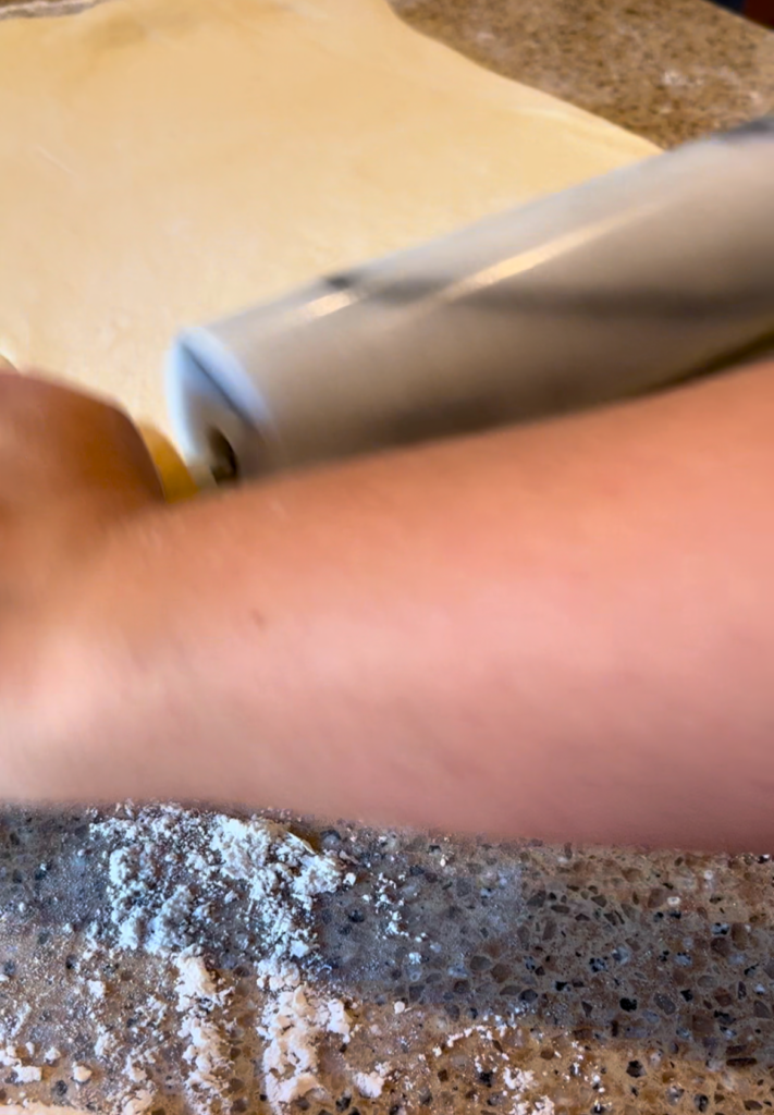 Woman rolling out dough with a grey rolling pin