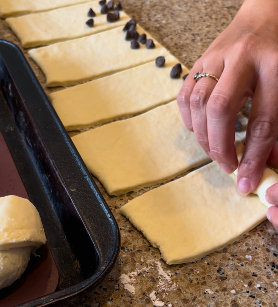 Woman rolling chocolate inside croissant dough