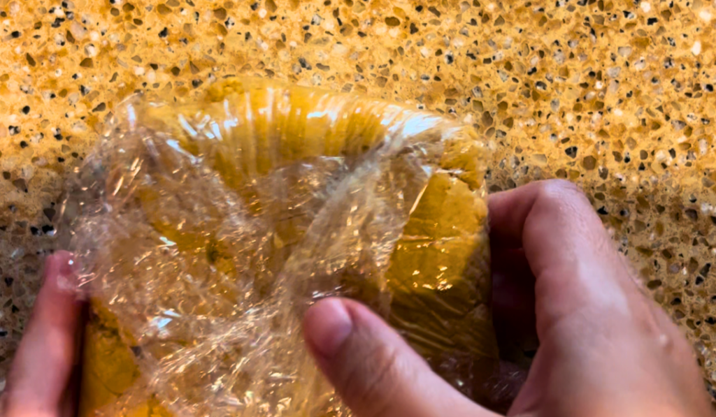 Woman holding cookie dough in cling-film