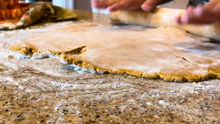 Woman rolling out cookie dough with a wooden rolling pin
