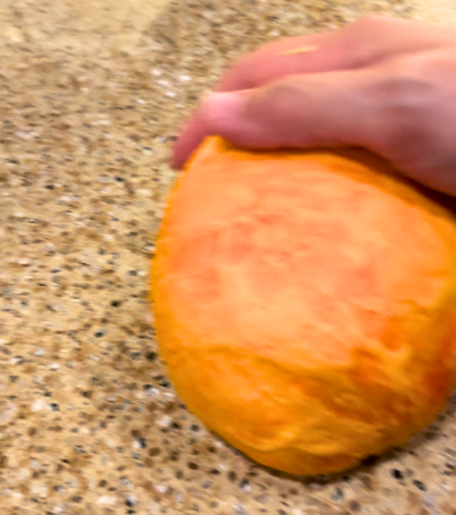 Woman kneading orange dough