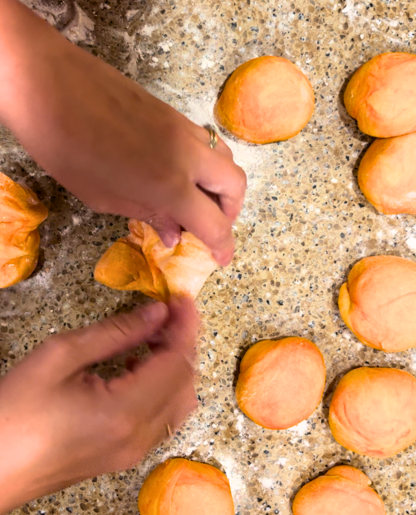 Woman forming orange dough into balls