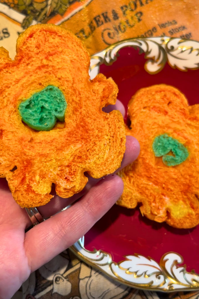 Woman holding a cooked pumpkin shaped bagel cut in half