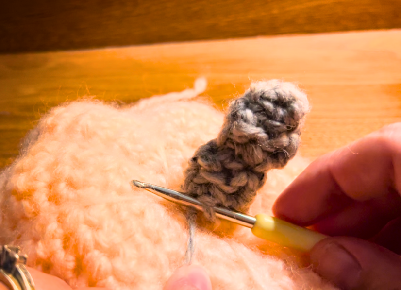 Woman inserting a crochet hook into the stem of a crochet pumpkin
