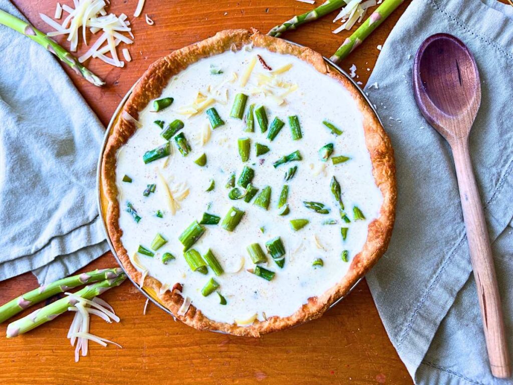 An unbaked asparagus and Swiss cheese quiche.