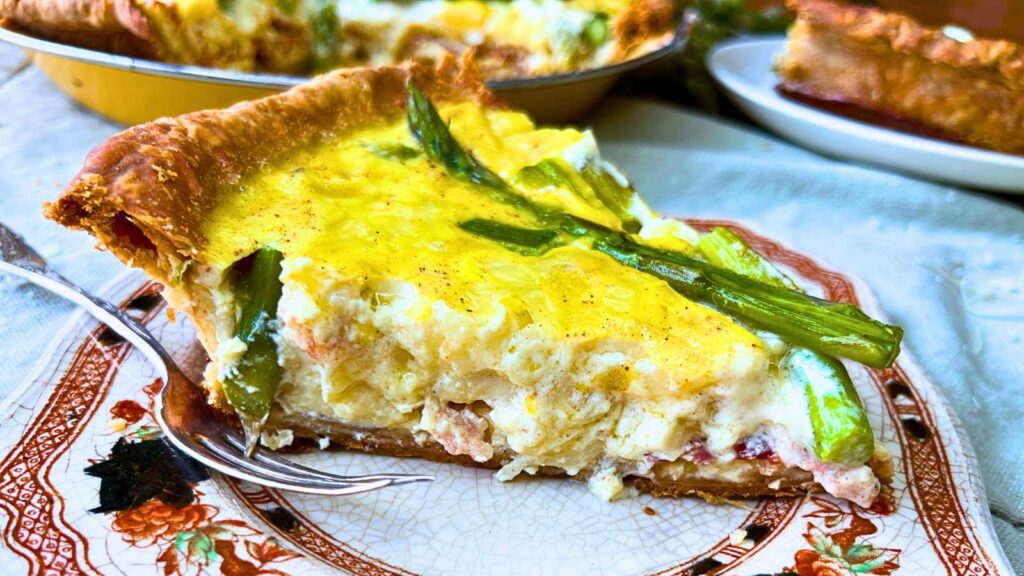 A side view of a slice of asparagus and bacon quiche.