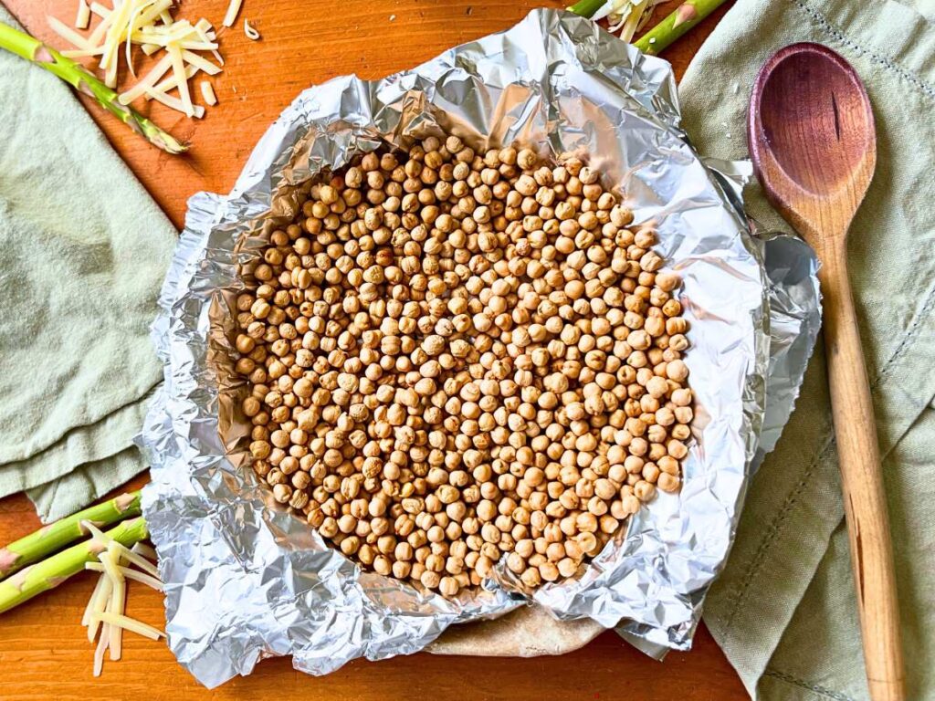 A pie crust with tin foil and dried chickpeas inside.