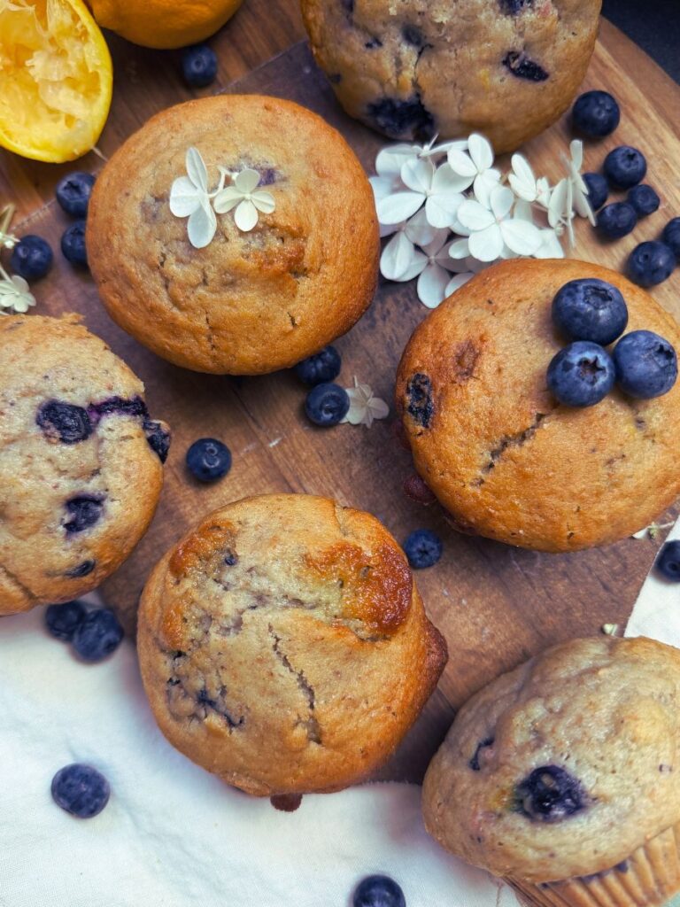 A collection of blueberry muffins on a wooden board.