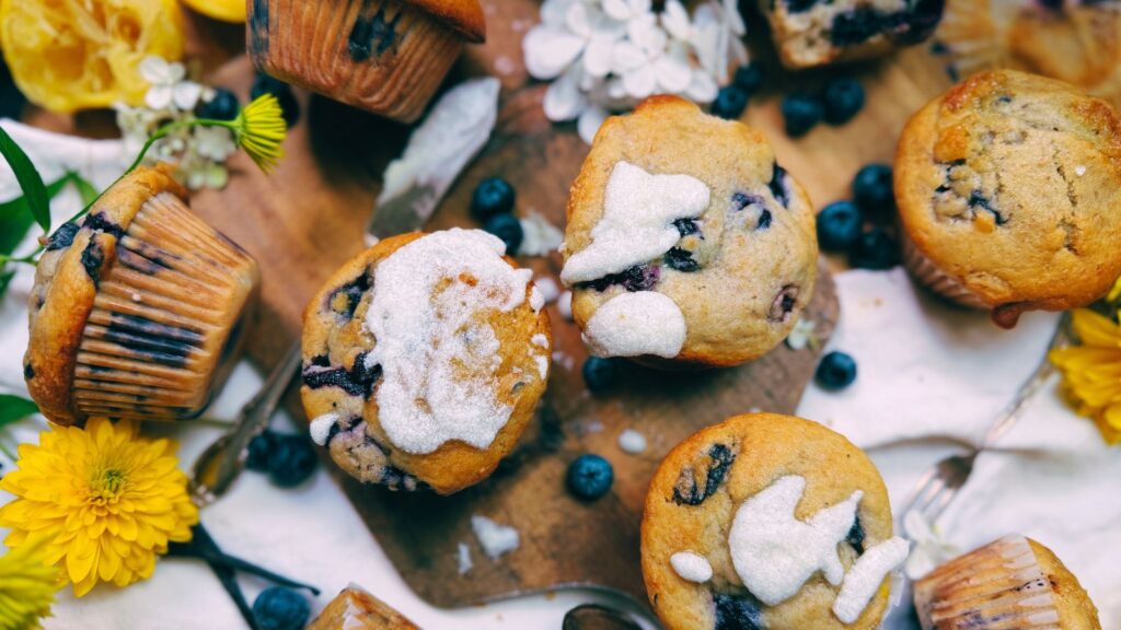 A collection of blueberry muffins. Some have a vanilla glaze.