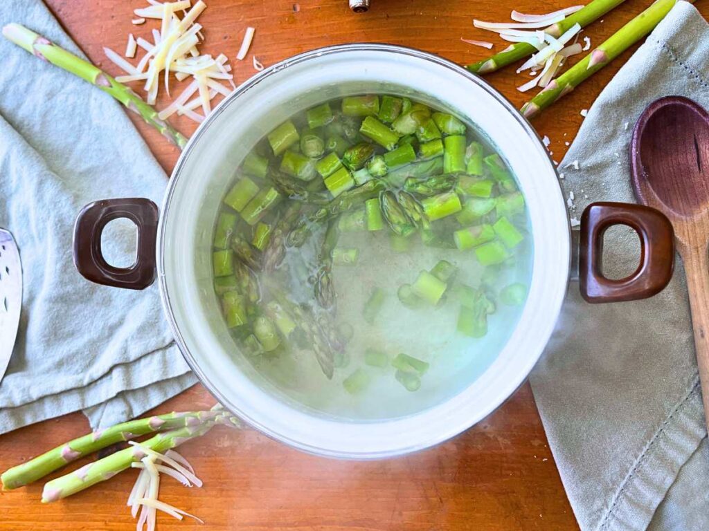 A pot of chopped asparagus in boiling water.