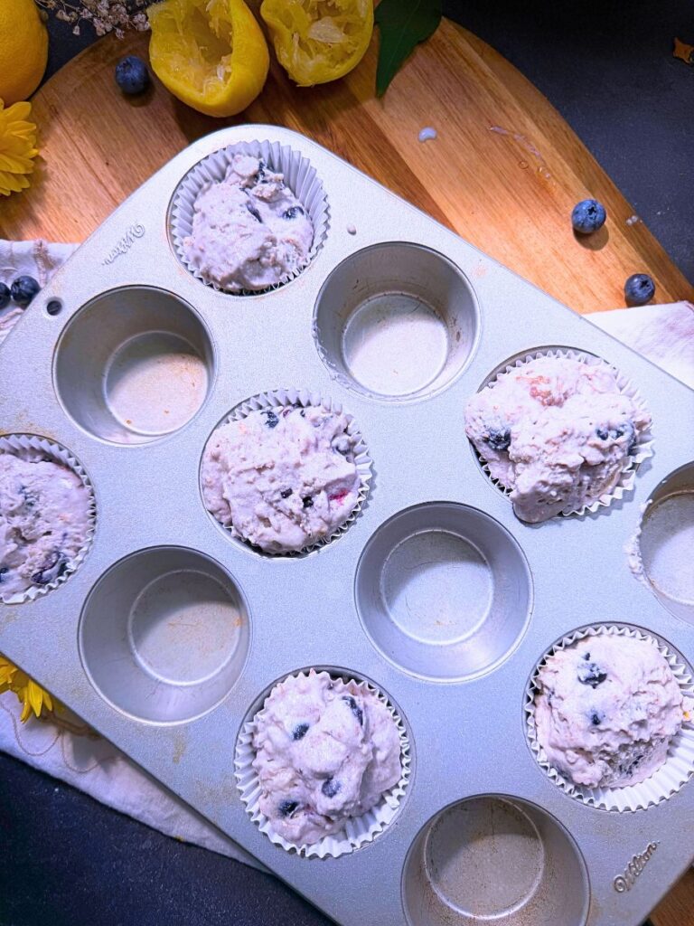 Lemon blueberry muffin batter in a lined muffin tin.
