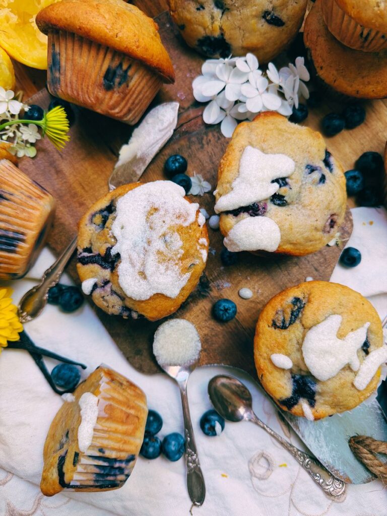 A collection of blueberry muffins. Some have a vanilla glaze on top.