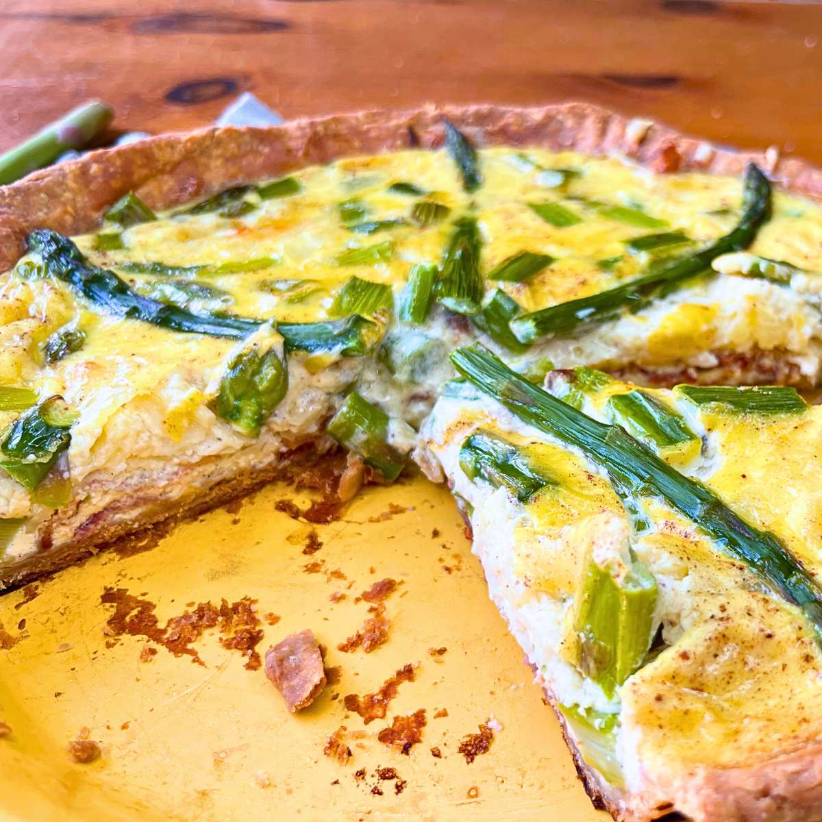 An asparagus and Swiss quiche that has been sliced in a yellow pie plate.