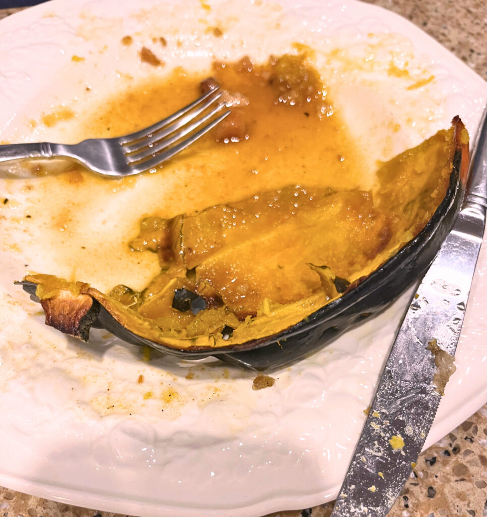 A finished plate with the skin of an acorn squash and a fork and knife.