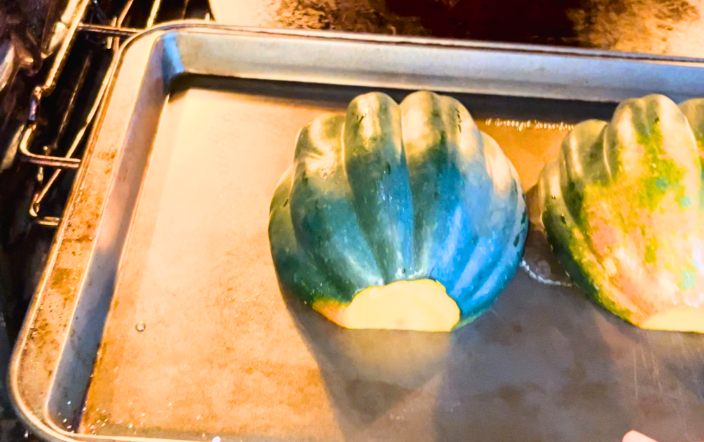 putting an acorn squash in the oven, on a cookie sheet.