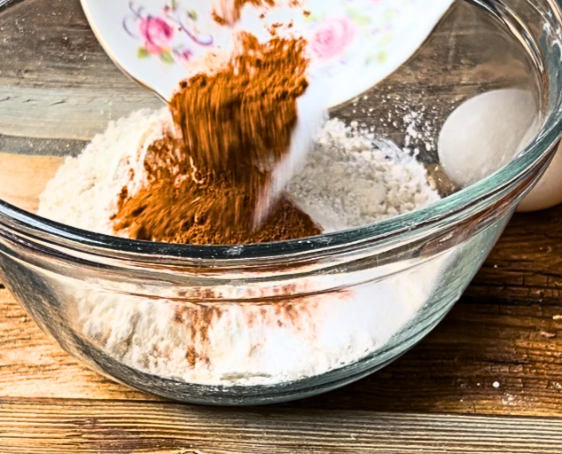Pouring a dish with cinnamon and salt into a glass bowl of flour.