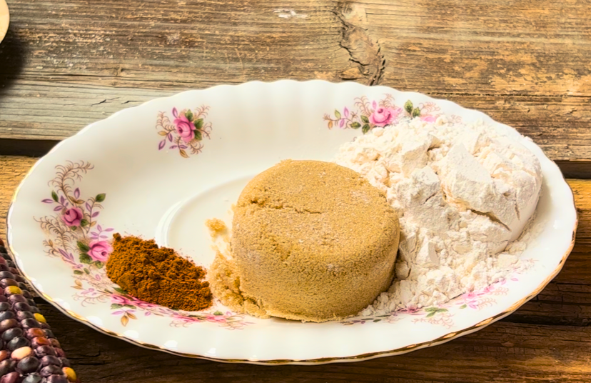 A white oval plate with pink flowers. On the plate is flour, brown sugar, and cinnamon