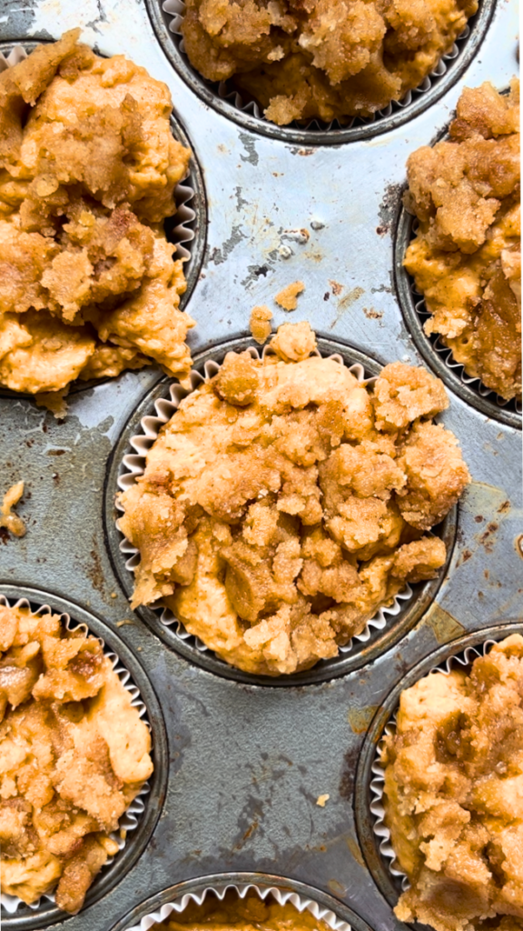 A muffin tray with pumpkin muffin batter and streusel topping.