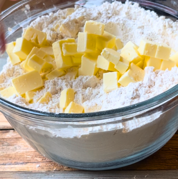 A glass bowl with a flour mixture and cubed butter.