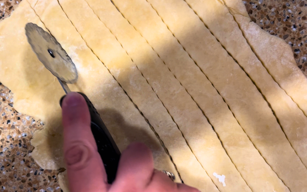 Woman cutting strips of pastry dough with a rotary cutter
