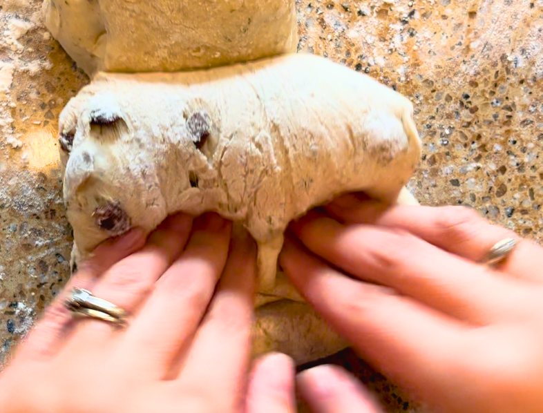 A woman folding herb stuffing bread dough into a log